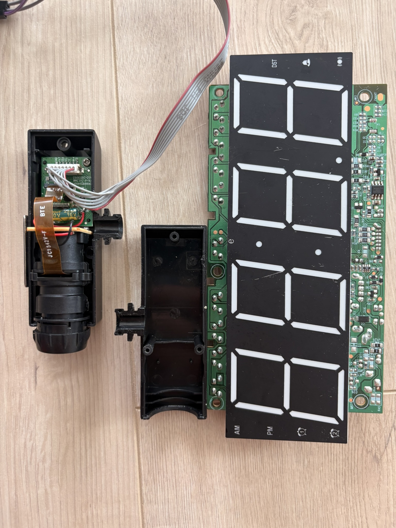 the opened clock showing the two separate modules side by side — the main clock board and the detached projector module