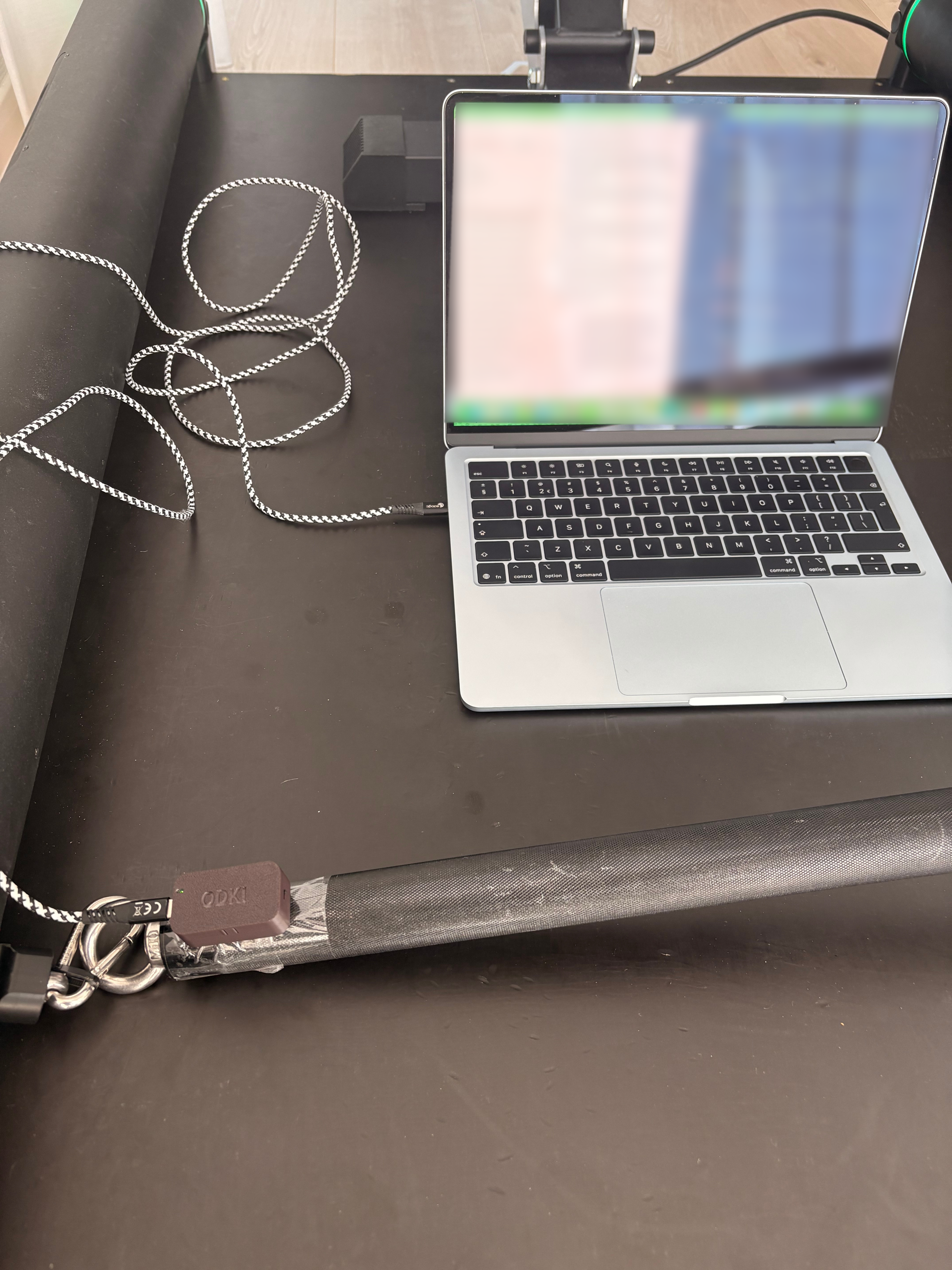 The experiment setup: the prototype IMU device and the reference sensor both mounted on the barbell, connected via Bluetooth to a laptop running the Python data logger and Claude Code agent.